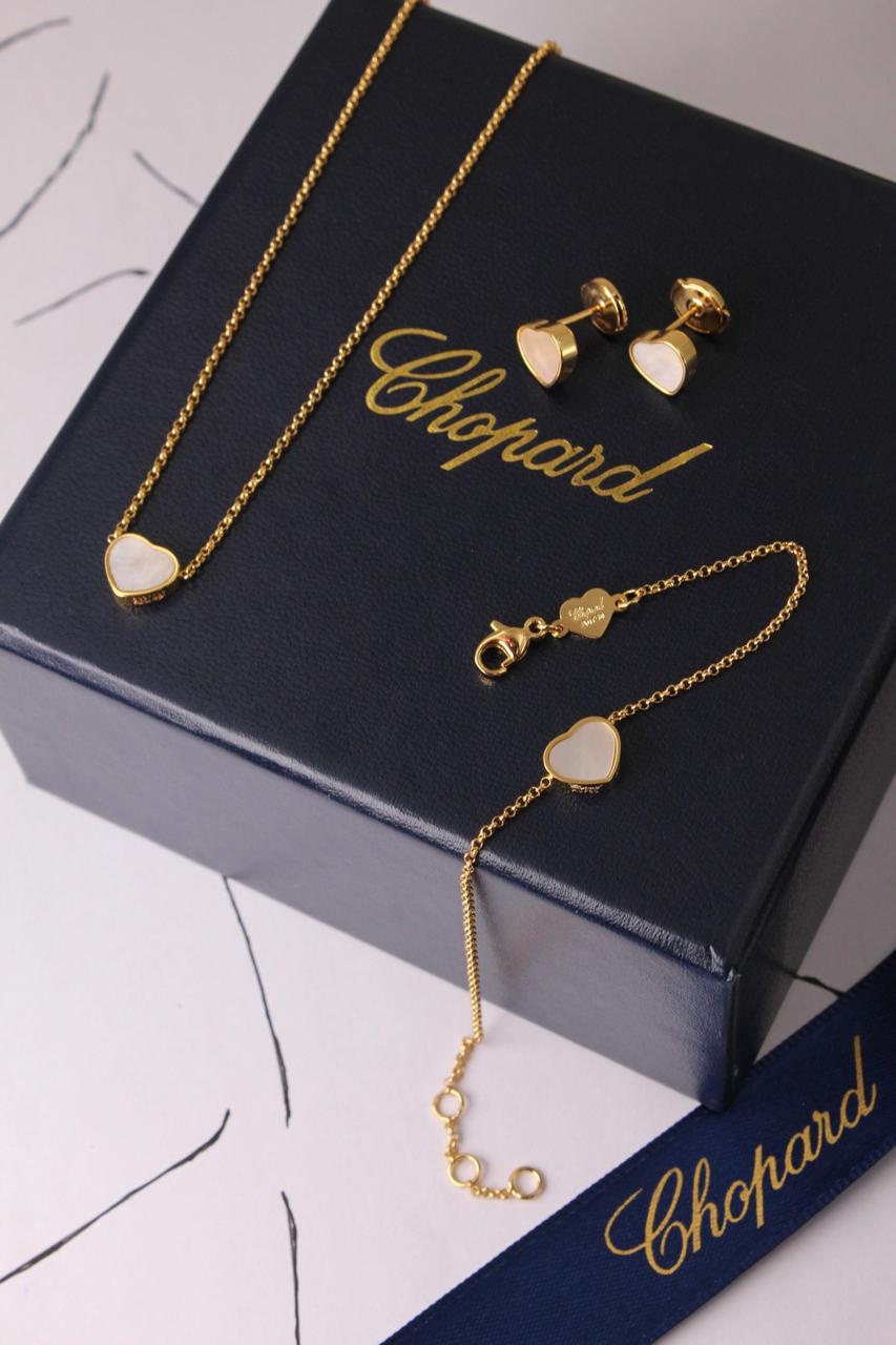 Chopard Happy Hearts-Inspired Three-Piece Jewelry Set — -Tone Heart Pendant Necklace, Matching Stud Earrings & Delicate Chain Bracelet with White Mother-of-Pearl Heart Motifs.
