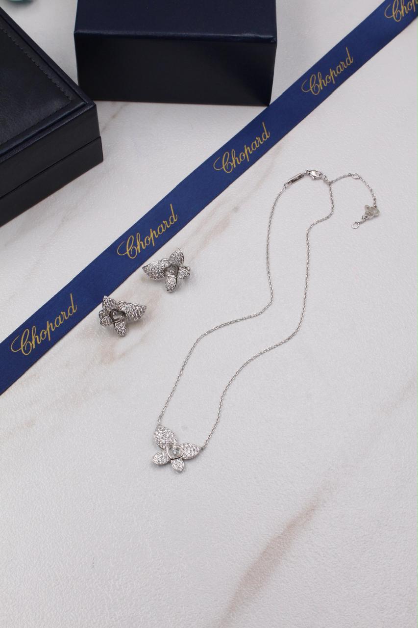 Chopard Happy Diamonds Butterfly Necklace & Earrings Set — White-Tone Metal with Pavé-Set Stones and Heart-Shaped Floating Diamond Details.