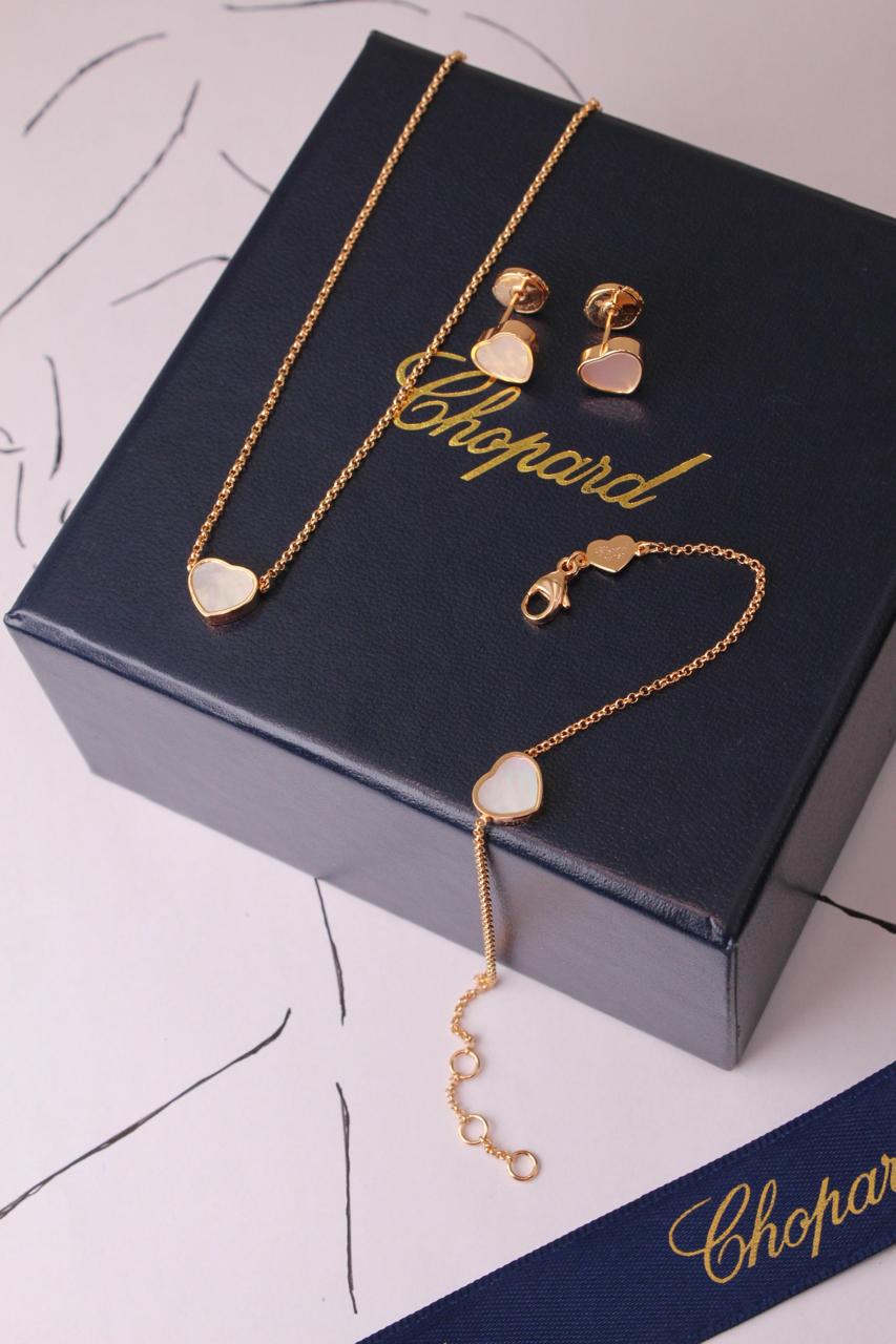 Chopard Happy Hearts-Inspired Three-Piece Jewelry Set — -Tone Heart Pendant Necklace, Matching Stud Earrings & Delicate Chain Bracelet with White Mother-of-Pearl Heart Motifs.